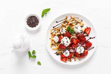 Fototapeta na wymiar Belgian waffles with fresh strawberry, chocolate topping and whipped cream