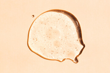 Squeezed cosmetic clear cream gel texture. Close up photo of transparent drop of skin care product. High Quality transparent gel with bubbles closeup on beige background.