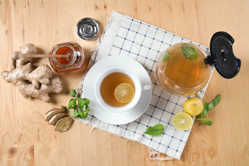 Top view of cup of hot ginger tea with honey, lemon and mint with steam from cup on wooden table over black background. the concept of natural medicine.