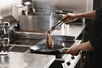 Female chef cooking chicken fillet on stove in restaurant  kitchen, closeup