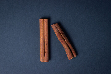 Cinnamon on a black background. Two cinnamon sticks, one next to the other. Photo from above