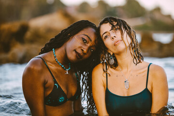 A beautiful couple of a black and a blonde woman in the water of the sea in a mediterranean beach...