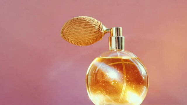 Luxury golden perfume bottle and shining light flares on pink background, glamorous fragrance scent as perfumery product for cosmetic and beauty brand, stock footage