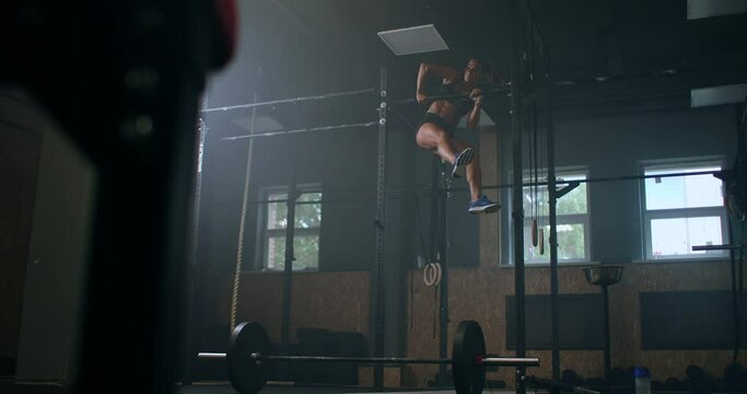 Female Athlete Swinging On Chin Up Bar. Strong women Doing Chin-ups On Gymnastic Bars In Gym. Professional Athlete Does Chin-up Power Strength and Cross Fitness Exercises and Everyday Workout Routine.