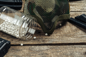 Close up of airsoft gun magazine and airsoft balls on wooden background