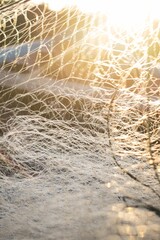 Vertical shot of a fishing net and sunlight coming through it
