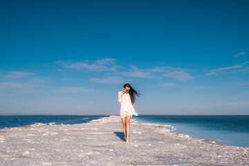Fototapeta na wymiar Beautiful girl in a beach dress by the sea. Woman on a salt lake. 