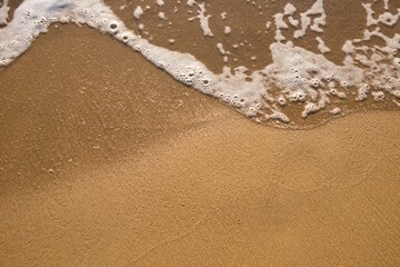 Fototapeta na wymiar Foamed water on the sandy beach during the daytime