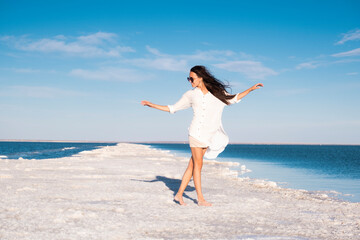 Fototapeta na wymiar Beautiful girl in a beach dress by the sea. Woman on a salt lake. Rest at the Dead Sea.