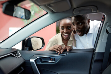 wow, look, what a chic car young african couple is interested in auto, they surprisingly look inside of car, in shock by design of car - obrazy, fototapety, plakaty