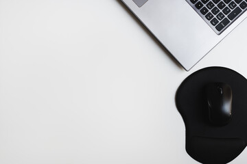 Laptop keyboard and computer mouse with ergonomic mouse pad for comfortable wrist position while working. Clean office desk flat lay