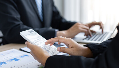 Young man in a black suit is analyzing financial graphs with a black woman in the office.