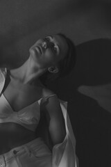 Naklejka premium Sexy Slavic beautiful woman posing at the studio wall wearing crop top. Vertical black-and-white image.