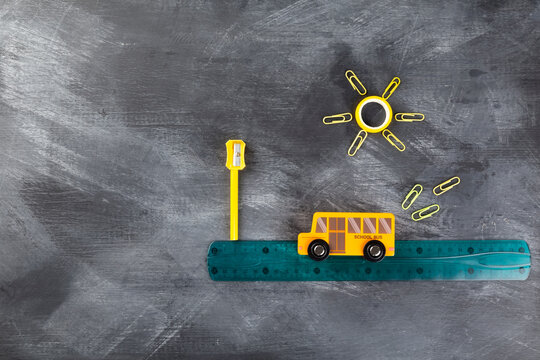 Back to school concept. Imitation of trip to school on school bus. Pencils, ruler, sharpener, toy bus on black background. Top view. Copy space © matucha12