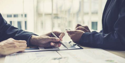 Young man in a black suit is analyzing financial graphs with a black woman in the office.