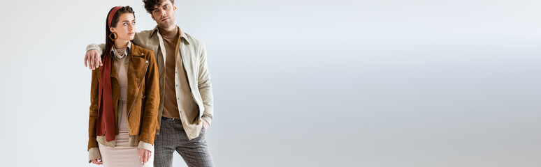 webside header of young, stylish couple in autumn clothes posing on grey