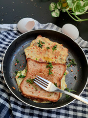 Bread Omelette Sandwich topped with fresh chili flakes, oregano & herbs on a plate.