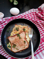 Bread Omelette Sandwich topped with fresh chili flakes, oregano & herbs on a plate.