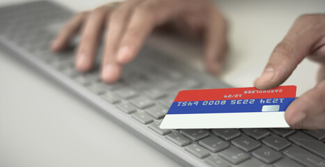 Man pays online with plastic bank card with printed flag of Russia. Fictional numbers