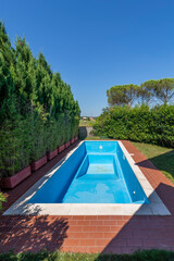 A swimming pool with blue coating in a private garden completely empty, waiting to be filled with water for the start of the summer season
