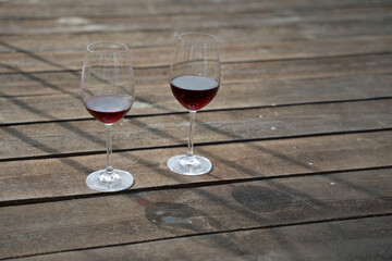 Two glasses of red wine with a shadow on a wooden background