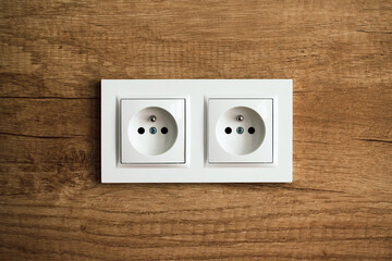 Electrical socket isolated on wooden kitchen wall. Renovated studio apartment power supply background. Empty copy space white plastic double power outlet.