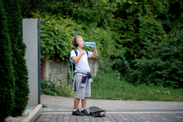 Cool little schoolboy skater boy drinking water. 