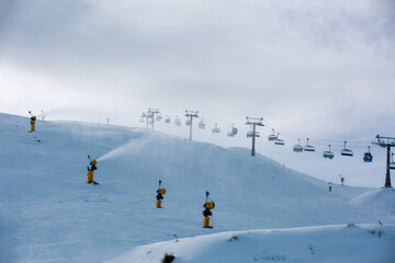 Naklejka na ściany i meble Snow making machine or snow gun at ski fields on snow peak.