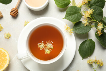 Flat lay composition with tasty tea and linden blossom on light grey marble table