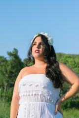 Pretty and brunette girl dressed as a bride in a garden