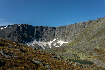 The concept of outdoor activities in the mountains. Minimalist mountain landscape with a snowy field on the pass, with snow on the side of the mountain.