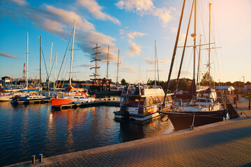 Boats in the port against the setting sun. Moored boats by the sea, sunset. The concept of sailing, spending time on a boat, sailboat.