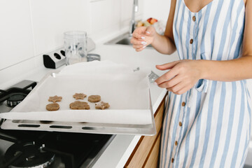 Woman puts cookies on baking sheet. Homemade baking. Cooking at home concept. Selective focus.