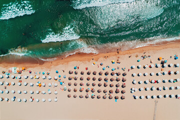Aerial top view on the beach. Umbrellas, sand and sea waves