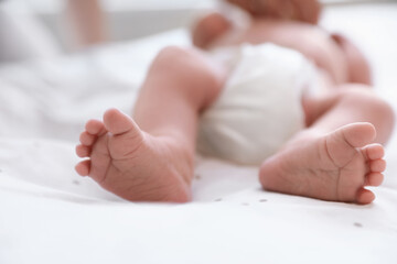 Newborn baby lying on bed, closeup of legs