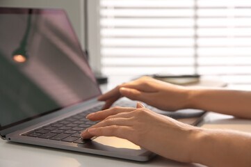 Woman working with modern laptop at white table, closeup