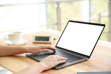 Woman working with modern laptop at wooden table, closeup