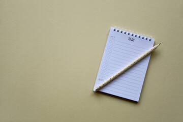 Notepad with pencil on a beige paper background. Top view. Close-up. Flat lay.