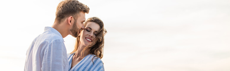 panoramic shot of happy girl smiling near cheerful boyfriend outside