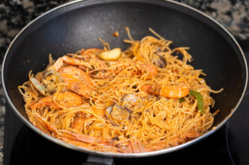 Frying pan with spaghetti and seafood in wok
