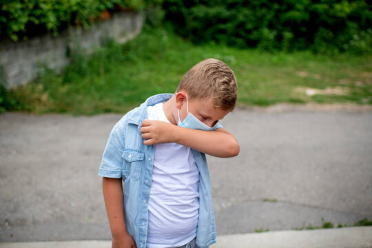 A Young  Blond Caucasian Boy Demonstrating The Correct Way To Cough And Sneeze Into An Elbow Rather Than Using Hands To Stop The Spreading Of The Corona Virus During Lock Down 