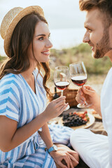 cheerful couple clinking glasses with red wine outside