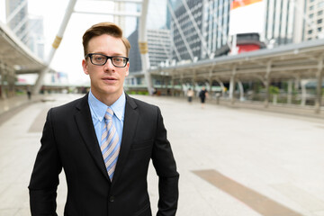 Young handsome blond businessman with eyeglasses in the city outdoors