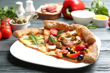 Slices of different delicious pizzas on grey wooden table, closeup