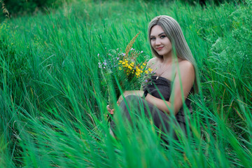 girl with a bouquet of wildflowers in the grass	