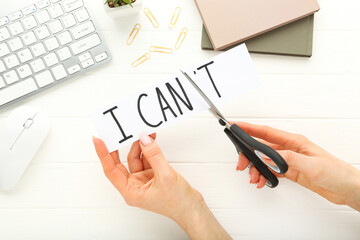 Female hands using scissors for cutting word I Can't and keypad and notepads