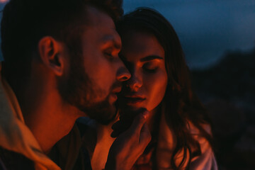 selective focus of bearded man touching attractive woman at night
