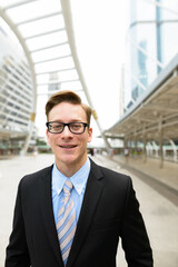 Happy young handsome blond businessman with eyeglasses in the city outdoors