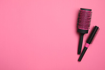 Modern round hair brushes on pink background, flat lay. Space for text