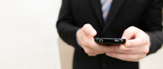 Hands of young businessman using phone in the city outdoors